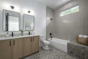 Full bath with washtub / shower combination, double vanity, and dark tile patterned floors