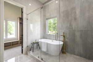 Bathroom with tile walls, light tile patterned floors, a freestanding tub, and light colored carpet