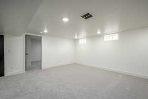 Below grade area with light carpet and recessed lighting