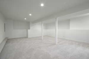 Finished below grade area with light colored carpet and recessed lighting