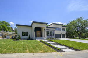 Modern home with stucco siding, driveway, a front yard, and an attached garage