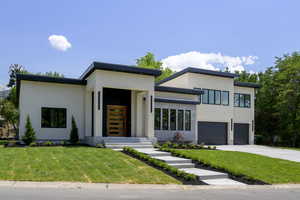 Modern home featuring a front lawn, stucco siding, and concrete driveway