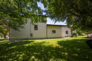 Rear view of house featuring a patio, a lawn, and stucco siding