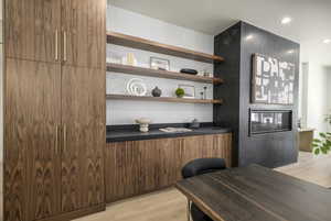 Bar featuring dark countertops, light wood finished floors, modern cabinets, recessed lighting, and open shelves