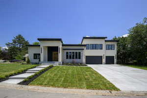 Modern home with stucco siding, a garage, driveway, and a front yard