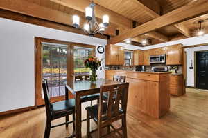 Dining room with light wood finished floors, a wood ceiling with exposed beams, and a chandelier