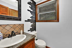 Half bath featuring vanity and tasteful backsplash