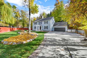 Colonial inspired home with driveway, a chimney, an attached garage, and roof with shingles