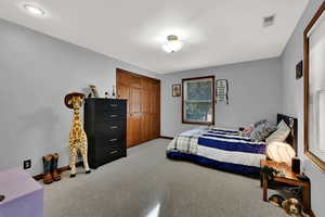 Bedroom with light colored carpet and a closet
