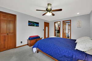 Bedroom featuring carpet, a ceiling fan, a walk in closet, connected bathroom, and recessed lighting