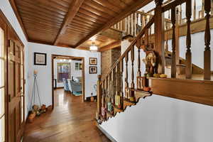Stairway featuring a wooden ceiling with exposed beams and hardwood / wood-style flooring
