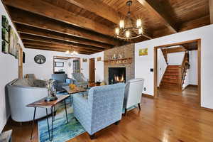Living area with a chandelier, stairway, wood finished floors, a fireplace, and a wooden ceiling with exposed beams