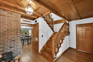 Stairway featuring wood-type flooring, a chandelier, and a wood ceiling with exposed beams
