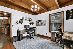 Home office featuring dark wood-style flooring, a chandelier, and a wooden ceiling with exposed beams