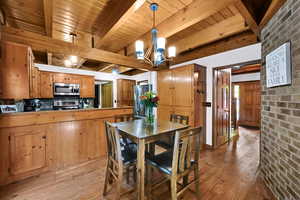Dining area with light wood-style flooring, a chandelier, and a wood ceiling with exposed beams