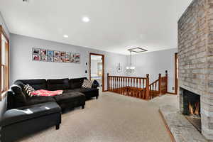 Carpeted living room featuring recessed lighting, a chandelier, and a brick fireplace