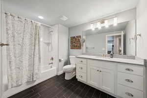 Full bath featuring shower / bath combo with shower curtain, vanity, a textured ceiling, and wood finish floors