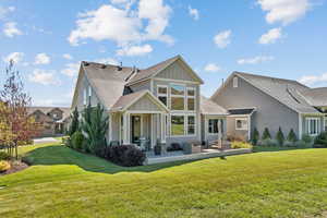 Back of house featuring board and batten siding, a shingled roof, and a yard