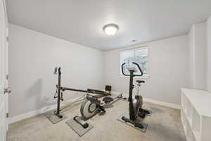 Exercise room with light carpet and a textured ceiling