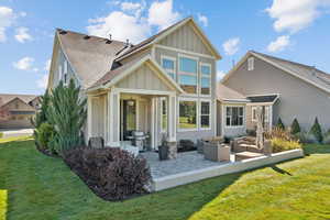 Back of house with a lawn, board and batten siding, a shingled roof, a patio area, and outdoor lounge area