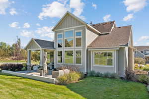 Back of house with a shingled roof, a lawn, board and batten siding, and stucco siding