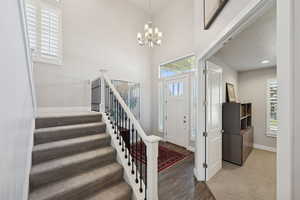 Entrance foyer featuring stairway, light wood finished floors, a high ceiling, and a chandelier
