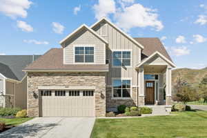 Craftsman-style home with board and batten siding, a shingled roof, stone siding, and a garage