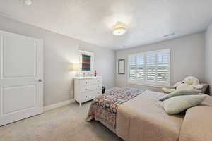 Bedroom with light colored carpet and a textured ceiling