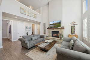 Living room with wood finished floors, a high ceiling, and a fireplace
