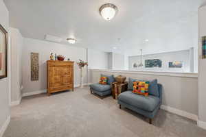 Living area featuring light colored carpet and a textured ceiling