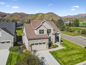 Craftsman house featuring stone siding, board and batten siding, roof with shingles, driveway, and a front lawn