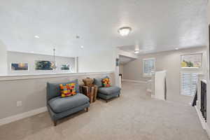 Sitting room featuring an upstairs landing, carpet floors, a textured ceiling, and recessed lighting