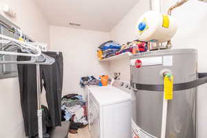 Laundry area with secured water heater, washer and dryer, and light tile patterned floors