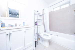 Full bath with shower / bath combination with curtain, vanity, and light tile patterned flooring