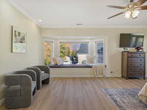 Living area featuring light wood-type flooring, a ceiling fan, crown molding, and recessed lighting