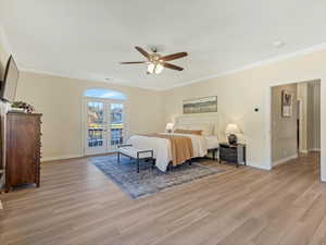 Bedroom featuring crown molding, french doors, a ceiling fan, access to outside, and light wood-style floors
