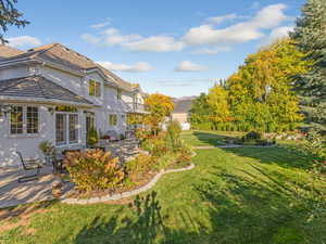 View of grassy yard featuring a patio area and a balcony
