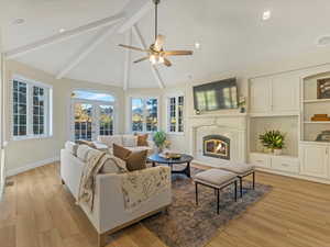 Living area featuring beam ceiling, a fireplace, light wood-style flooring, recessed lighting, and a ceiling fan