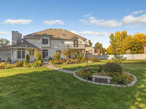 Rear view of property featuring stucco siding, a balcony, and a chimney