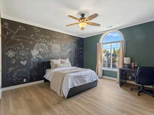 Bedroom featuring ornamental molding, wood finished floors, a ceiling fan, and a desk