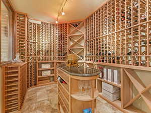 Wine room with a textured ceiling, track lighting, and light stone finish flooring