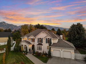 Traditional home featuring a mountain view, driveway, an attached garage, a chimney, and a gate
