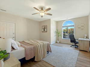 Bedroom featuring light wood-style flooring, ceiling fan, and an office area