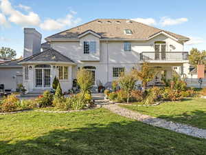 Back of property featuring a lawn, a balcony, and stucco siding