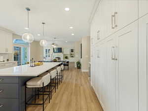 Kitchen featuring white cabinetry, a breakfast bar area, pendant lighting, a ceiling fan, and open floor plan