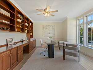 Office area with built in study area, crown molding, light wood-style floors, and ceiling fan