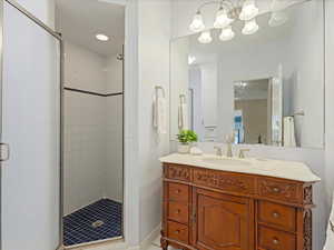Bathroom featuring vanity, a stall shower, and a chandelier