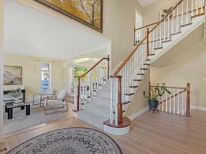 Foyer featuring light wood-style floors, a chandelier, a high ceiling, arched walkways, and stairs