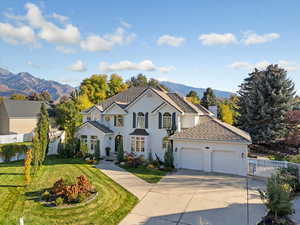View of front of home featuring driveway, a chimney, a mountain view, a garage, and stucco siding