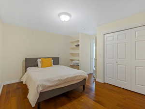 Bedroom featuring dark wood-style floors and a closet
